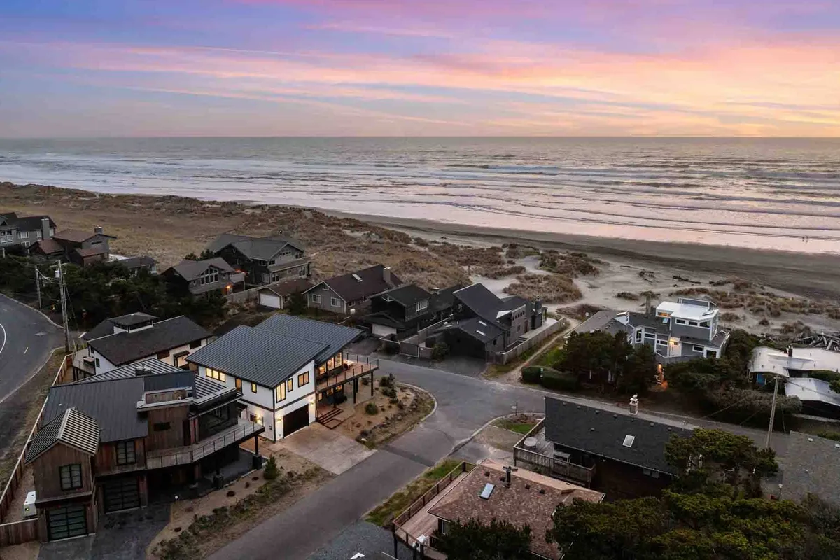 A beautiful view of the ocean at sunset, with beachfront properties in the foreground and a tranquil sky overhead. The inviting scene hints at the peaceful yet adventurous atmosphere available just steps from the home.